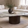 Modern organic marble coffee table with a polished veined marble top and a dark cylindrical solid wood base, styled in a quiet-luxury living room